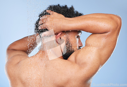 Image of Man, shower back and splash in studio with water, wash or hygiene with self care by blue background. Person, guy and muscle with hair, wellness or health for skin, natural dermatology and body