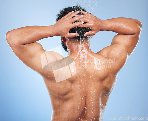 Image of Man, shower back and wash in studio with water, splash or hygiene with self care by blue background. Person, guy and muscle with hair, wellness or health for skin, natural dermatology and body