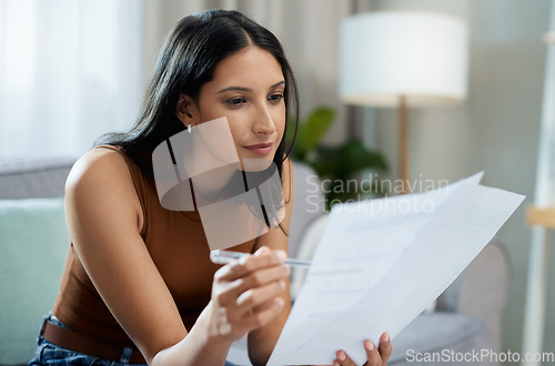 Image of Woman, documents and reading on sofa for finance, expenses or checking bills in living room at home. Face of female person with paperwork in budget planning, investments or financial plan at house