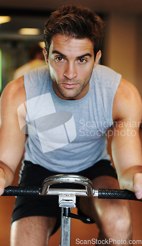 Image of Man, exercise bike and fitness at gym, endurance and training for competition, sweat and cardio. Male person, cycling and determination in workout, motivation and machine for wellness, club or class