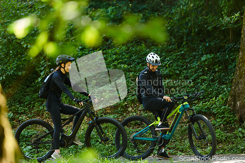 Image of A blissful couple, adorned in professional cycling gear, enjoys a romantic bicycle ride through a park, surrounded by modern natural attractions, radiating love and happiness