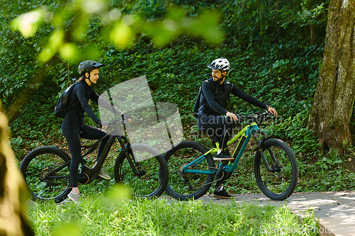 Image of A blissful couple, adorned in professional cycling gear, enjoys a romantic bicycle ride through a park, surrounded by modern natural attractions, radiating love and happiness