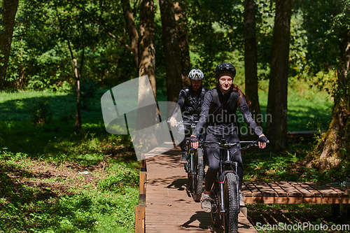 Image of A blissful couple, adorned in professional cycling gear, enjoys a romantic bicycle ride through a park, surrounded by modern natural attractions, radiating love and happiness