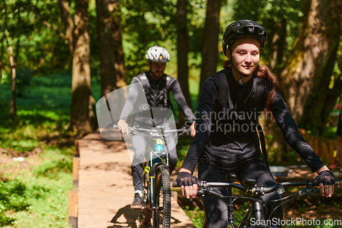 Image of A blissful couple, adorned in professional cycling gear, enjoys a romantic bicycle ride through a park, surrounded by modern natural attractions, radiating love and happiness