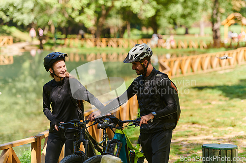 Image of A blissful couple, adorned in professional cycling gear, enjoys a romantic bicycle ride through a park, surrounded by modern natural attractions, radiating love and happiness