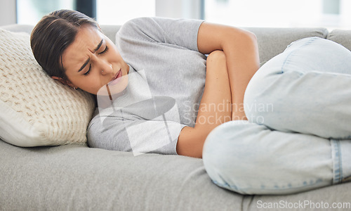 Image of Woman, stomach pain and stress on sofa, sick or menstruation with anxiety, gas or virus in home living room. Girl, abdomen and emergency for gut health, constipation or cramp on lounge couch in house