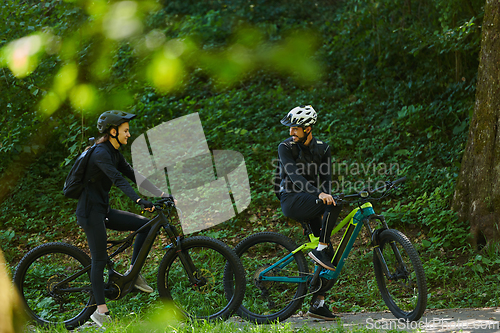 Image of A blissful couple, adorned in professional cycling gear, enjoys a romantic bicycle ride through a park, surrounded by modern natural attractions, radiating love and happiness