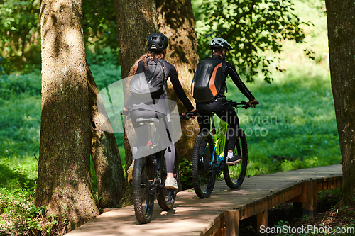 Image of A blissful couple, adorned in professional cycling gear, enjoys a romantic bicycle ride through a park, surrounded by modern natural attractions, radiating love and happiness