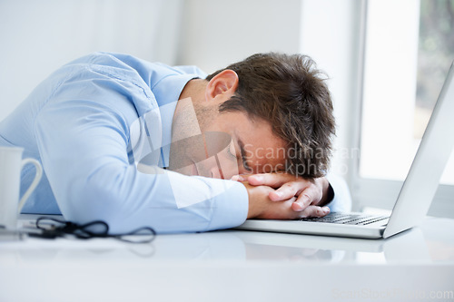 Image of Businessman, laptop and sleeping on office desk in burnout, stress or fatigue from pressure or overworked. Tired man or employee asleep on table with computer in mental health or anxiety at workplace