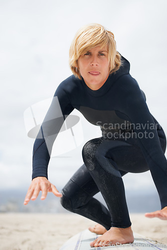Image of Portrait, beach and a man surfing instructor on sand, teaching balance, skill or technique. Fitness, summer and a young person in a wetsuit on a surfboard as a sports coach on the coast in Australia