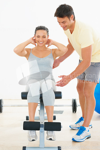 Image of Happy woman, personal trainer and sit ups on bench at gym for workout, exercise or indoor training. Man, coach or instructor helping female person on equipment for strong core or abs at health club