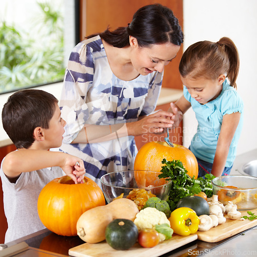 Image of Mom, daughter and son with pumpkins for halloween in the kitchen of their home for holiday celebration. Family, food or tradition and a woman teaching her kids how to carve vegetables in an apartment