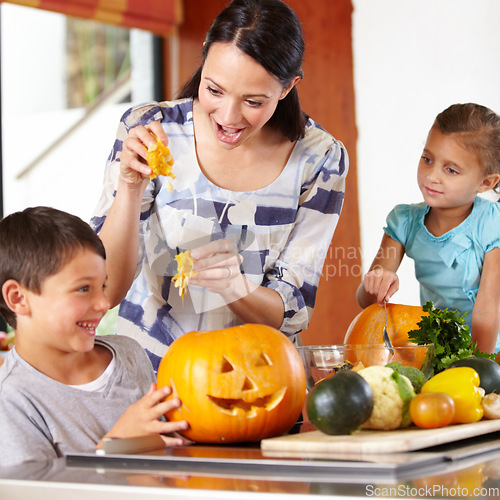 Image of Mother, girl and boy with pumpkins for halloween in the kitchen of their home for holiday celebration. Family, food or tradition and a woman teaching her young children how to carve vegetables