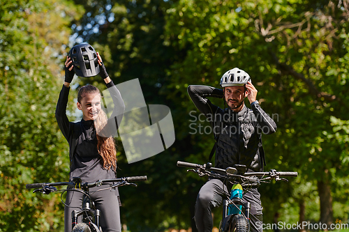 Image of A blissful couple, adorned in professional cycling gear, enjoys a romantic bicycle ride through a park, surrounded by modern natural attractions, radiating love and happiness