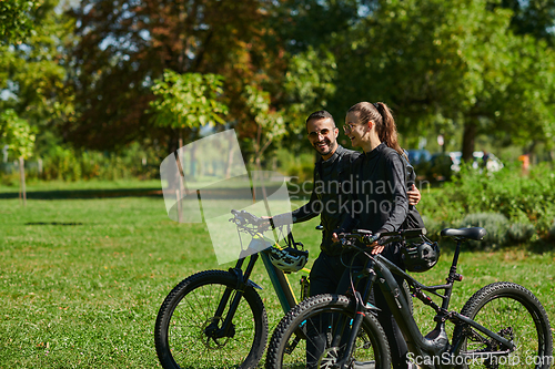 Image of A blissful couple, adorned in professional cycling gear, enjoys a romantic bicycle ride through a park, surrounded by modern natural attractions, radiating love and happiness