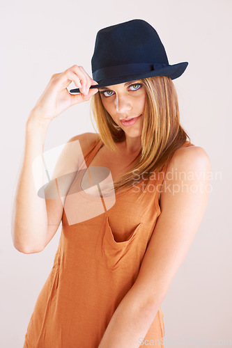 Image of Woman, fashion and portrait with hat in studio for confident, class and edgy attitude on wall background. Face, pose and female model with smart, casual or trendy outfit, unique style or fashionable