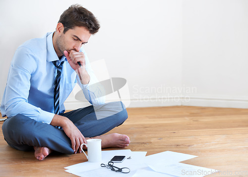 Image of Stress, documents and finance with a business man reading tax paper or a budget on the floor of his apartment. Accounting, compliance and anxiety with a young employee looking worried about debt