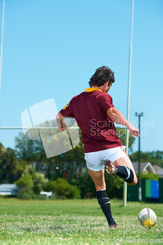 Image of Back, kick and man playing with rugby ball on a grass field to score during workout. Athlete, sport and professional player training for healthy workout in a uniform for kicking exercise with energy