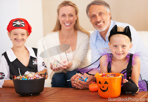 Image of Happy family, portrait and halloween party in home, trick or treat and happiness in childhood. Man, woman and kids for holiday with candy, pumpkin and fairy costumes for love and celebration in house