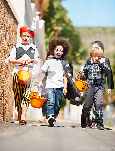 Image of Halloween, children or trick and treat portrait outdoor in neighborhood for fun and dress up. A group of young kids together for happiness, celebrate holiday and diversity with candy or sweets