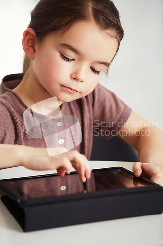 Image of Little girl, tablet and watching in living room for online entertainment, games or research at home. Face of young female person, child or kid with technology for communication or networking at house