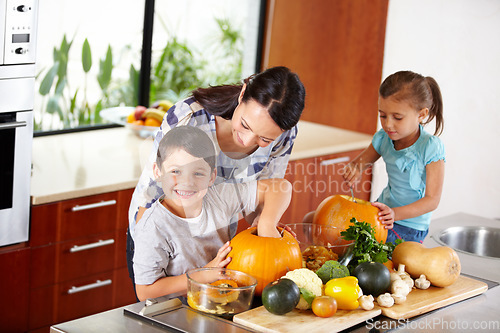 Image of Mother, sister and brother with pumpkins for halloween in the kitchen of their home for holiday celebration. Family, food or tradition and a woman teaching her sibling kids how to carve vegetables