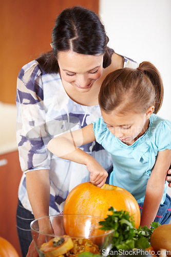 Image of Halloween, pumpkin and a woman in the kitchen with her daughter holiday celebration at home. Creative, smile or happy with a mother and girl child carving a vegetable for decoration or tradition