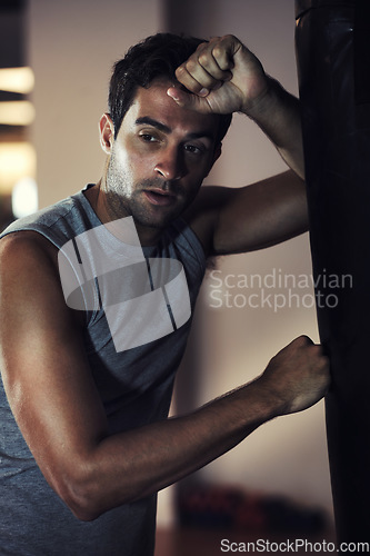 Image of Fitness, athlete and tired man after boxing class with rest for break during exercise workout. Health, wellness and male person with fatigue on a punching bag with sweaty sportswear in gym