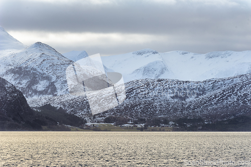 Image of Snow-Covered Mountain Range Overlooking the Calm Sea Under Cloud