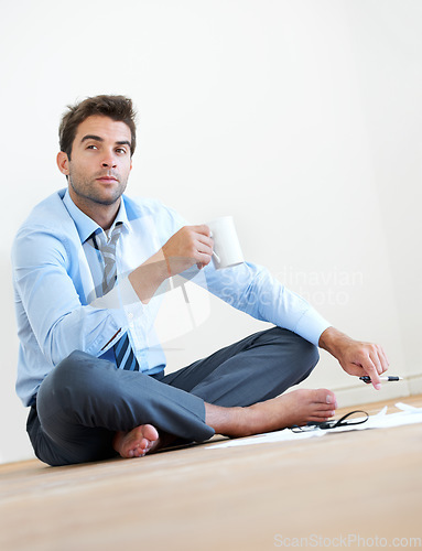 Image of Thinking, coffee and business man on floor in office for brainstorming, solution and problem solving. Corporate, professional and entrepreneur with ideas for company, career and job in workplace