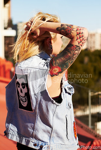 Image of Back, tattoo and a woman tying her hair outdoor in the city for travel, freedom or adventure on vacation. Fashion, style and a funky young punk rocker person looking at a view overseas or abroad