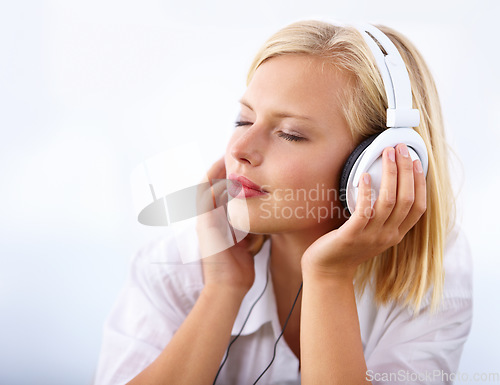 Image of Woman, relax and headphones for music on a white background for audio streaming service and mental health podcast. Student or calm person listening to music with dream, sleeping or peace in studio