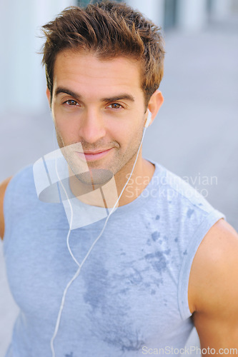 Image of Fitness, portrait and man athlete running with sweat on road for exercise, cardio or outdoor training. Active, sports and young male person with smile and earphones for music, playlist or album.