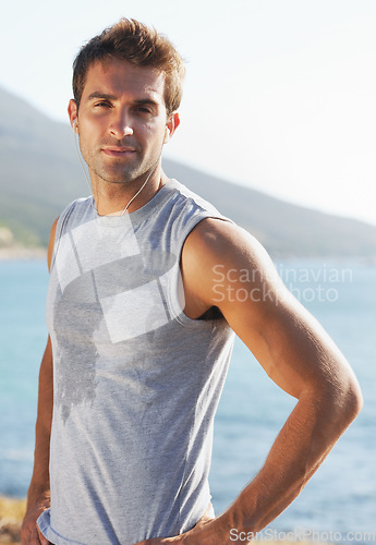 Image of Sports, portrait and man athlete running with sweat on road for exercise, cardio or outdoor training. Active, fitness and young male person with smile and earphones for music, playlist or album.
