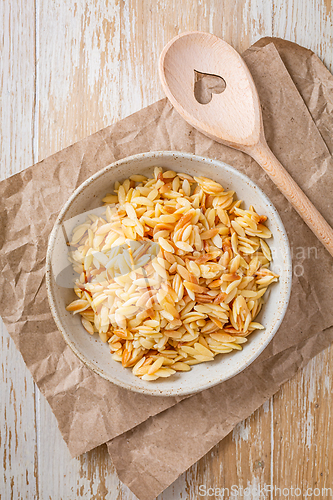 Image of Cooked italian pasta, risoni, orzo in a bowl on wooden table