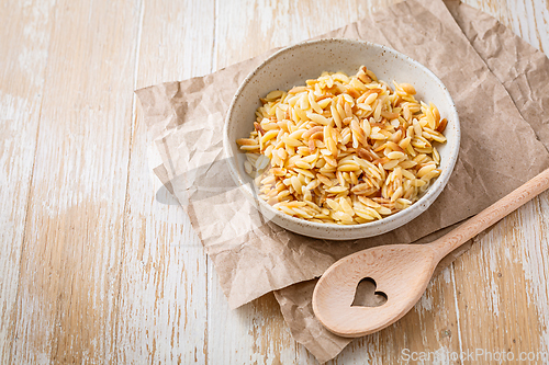 Image of Cooked italian pasta, risoni, orzo in a bowl on wooden table