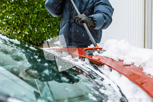 Image of Cleaning snow from windshield. Cleaning and clearing the car from snow on a winter day. 