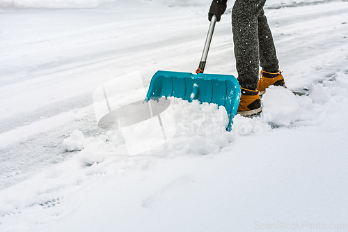 Image of Cleaning snow from street in winter with shovel after snowstorm. Cleaning sidewalk from snow on a winter day. 