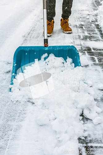 Image of Cleaning snow from street in winter with shovel after snowstorm. Cleaning sidewalk from snow on a winter day. 