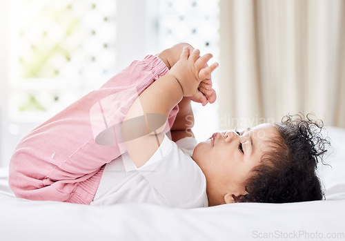 Image of Baby, feet and hands with curiosity in bedroom for motor skills, growth or development. Little girl, toddler and grab of toes, looking and playing with excitement, discovery and milestone in home