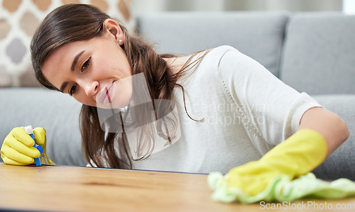 Image of Woman, cloth and gloves with spray on wood table, chemical and cleaning for hygiene in living room. Girl, cleaner and home in germ, fabric or maid for dust, shine and stop bacteria on furniture