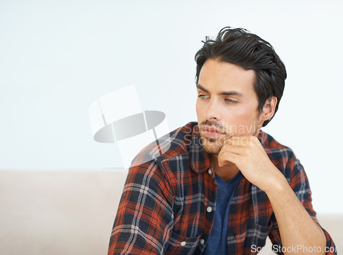 Image of Man, thinking and serious on sofa for question, idea and contemplating in living room of apartment or home. Person, face and mental health or thoughtful on couch in lounge for anxiety on weekend