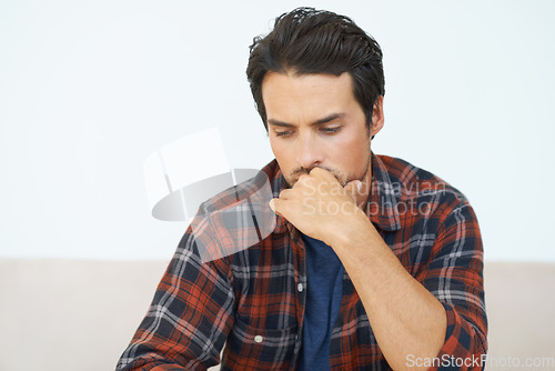 Image of Man, thinking and serious or hands for question, idea and contemplating in living room of apartment or home. Person, face and mental health or thoughtful on couch in lounge for anxiety or nervous