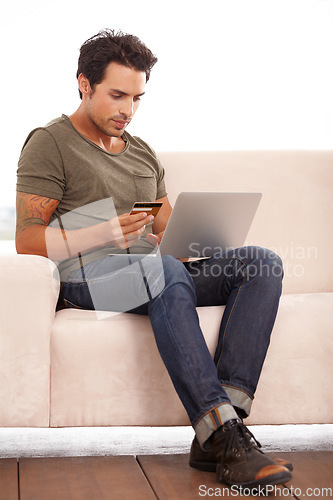 Image of Credit card, laptop and man on sofa for online shopping, e commerce and digital payment on fintech software. Person on couch, typing on computer and internet banking for financial investment or sale