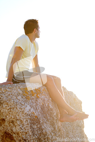 Image of Man, sitting or rock and cliff in nature for travel, adventure or scenery with sunshine, thinking and view. Person, mountain or sky for holiday, vacation or experience outdoor and freedom or barefoot