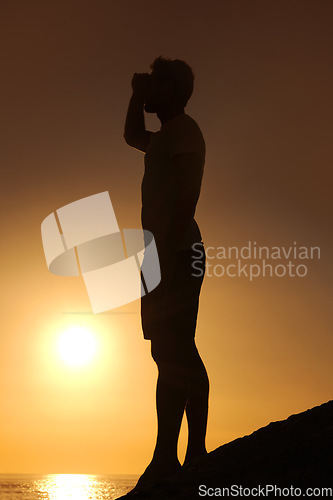 Image of Silhouette, man or looking with hands for view, scenery and wellness on beach with sunset and peace. Person, shadow or adventure and relax for holiday, vacation or experience by ocean or sea with sun