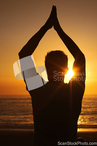 Image of Silhouette, man and praying with hands for yoga, health and wellness on beach with sunset and zen. Person, shadow and pilates or namaste for balance, mindfulness and healthy body by ocean or sea