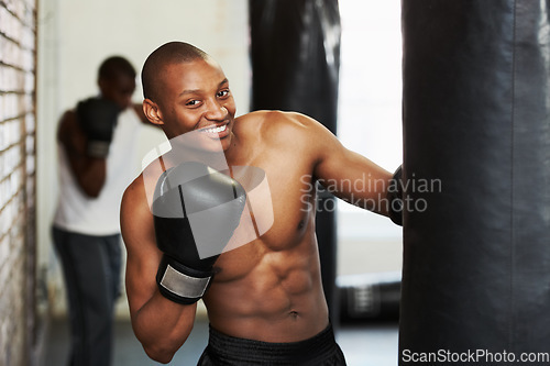 Image of Boxing, gloves and portrait of black man with bag, smile and fitness, power and training challenge. Strong body, muscle and happy boxer in gym, athlete with confidence and pride in competition fight
