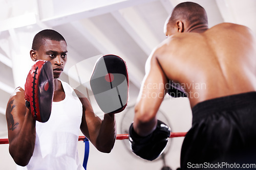 Image of Black man, boxer and personal trainer in self defense or ring fight at gym workout, exercise or training together. African male person with boxing or sparing partner preparing for sports competition