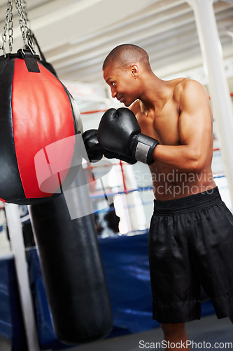 Image of Black man, boxing and punching bag at gym for workout, exercise or self defense practice in fighting sport. African male person or boxer with gloves for indoor training or martial arts at health club